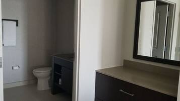 A bathroom with a toilet, a dark vanity with a mirror, and a towel rack.