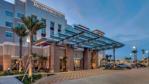 A modern hotel with a covered entrance, palm trees, and a parking area. - Residence Inn by Marriott Corpus Christi Downtown (Corpus Christi)