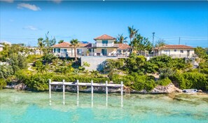 Situated on a lush landscape, this coastal property features buildings with red-tiled roofs, surrounded by dense vegetation and palm trees.