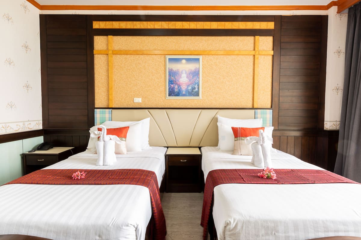 A hotel room with two beds, a nightstand with a phone, and a framed picture on the wall.