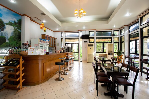 A restaurant with a bar area, multiple tables, and chairs. - Surin Majestic Hotel (Surin)