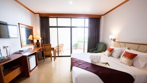 Habitación de hotel con cama, escritorio con computadora, silla, televisor y balcón con vistas.