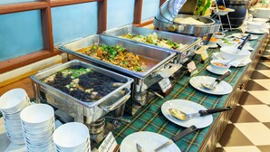 Un bufé con diferentes estaciones de comida y platos blancos apilados.