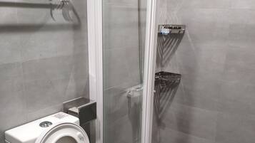 Een moderne badkamer met toilet, hygiëneschuimer en douchecabine.