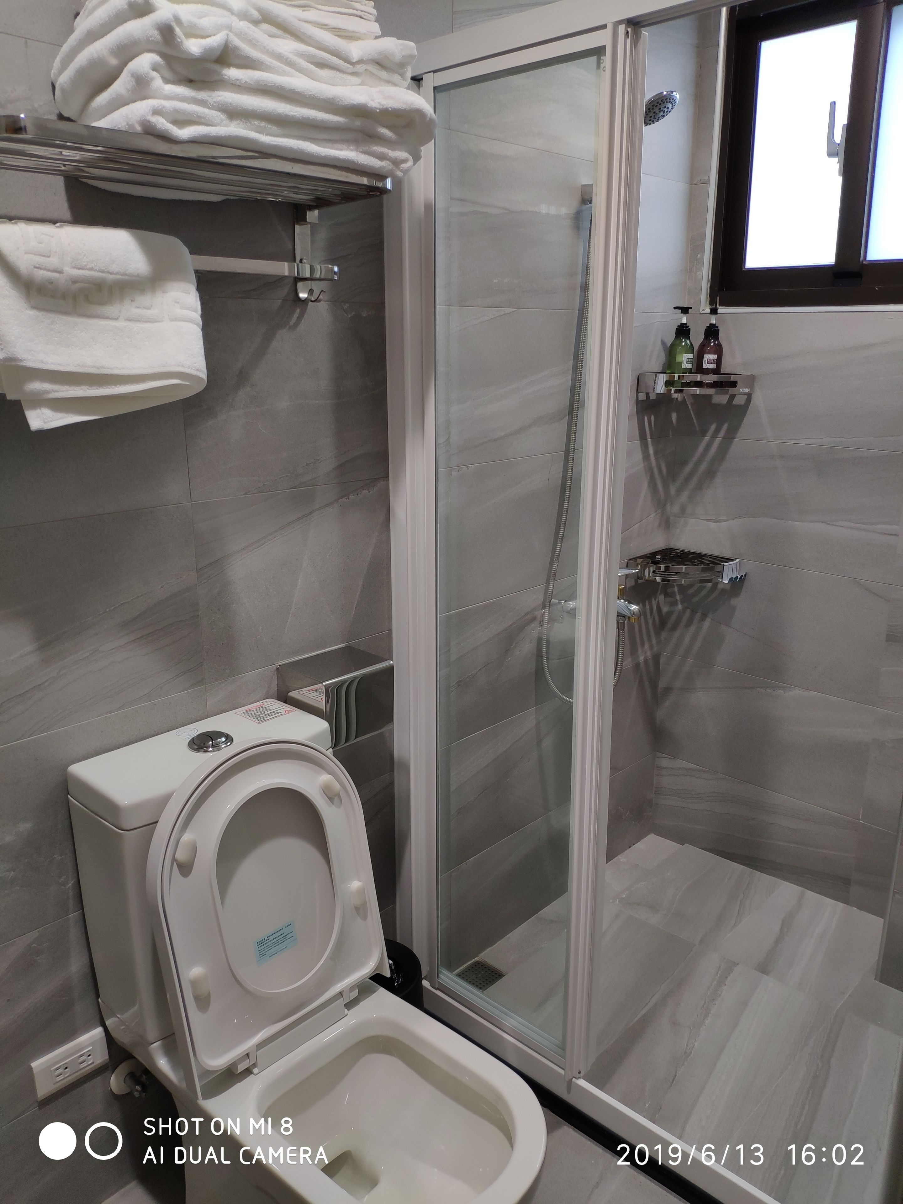 Un baño moderno con inodoro, ducha con mampara de vidrio y un perchero para toallas.