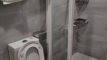Un baño moderno con inodoro, ducha con mampara de vidrio y un perchero para toallas.