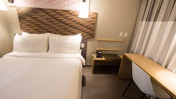 Ein Hotelzimmer mit Bett, Schreibtisch, Stuhl und Telefon.