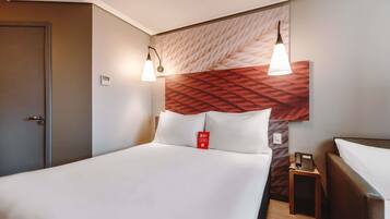 A hotel room with a bed, bedside table, and a wall-mounted telephone.