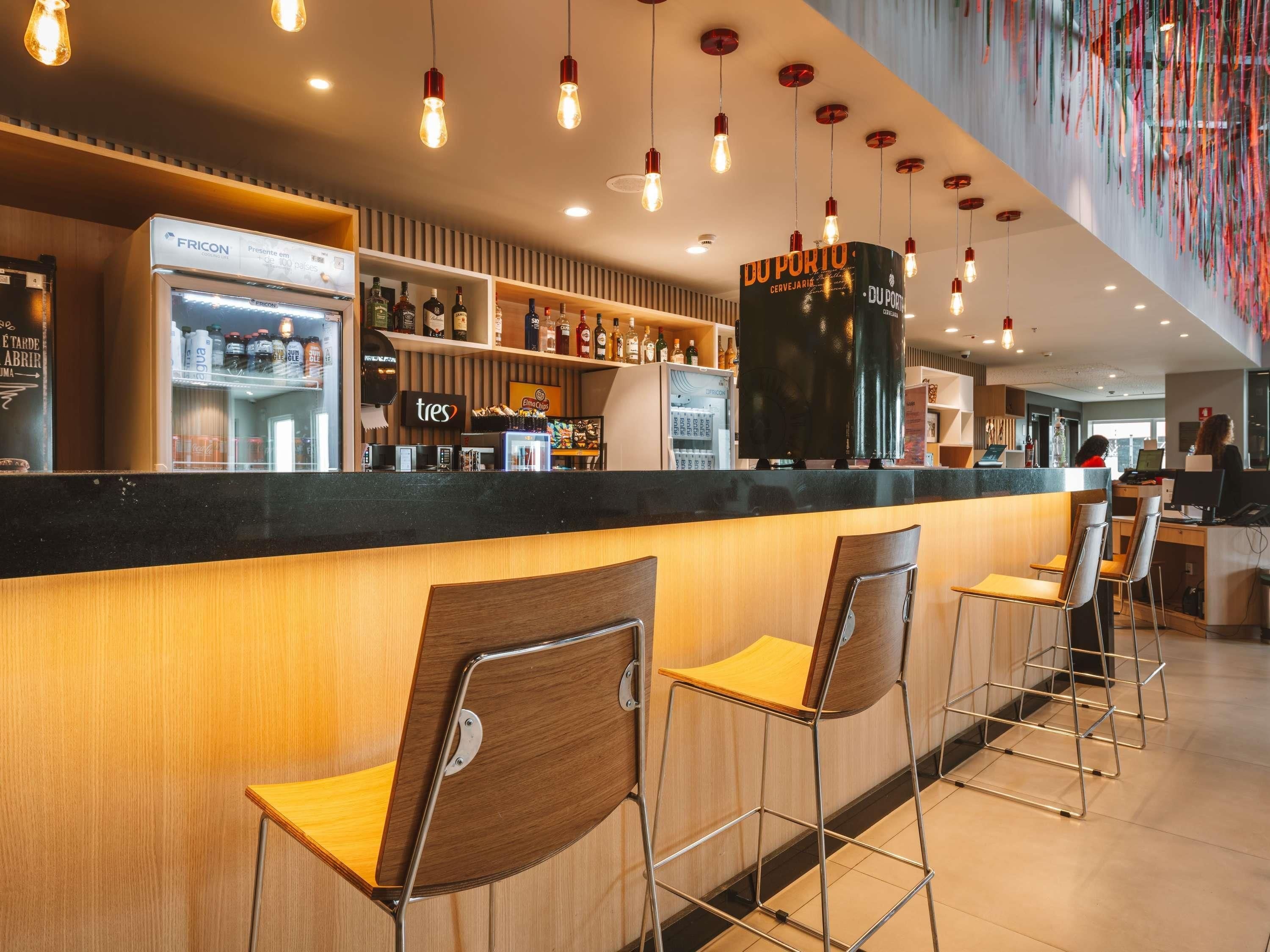 Zona de bar con barra, taburetes y estanterías llenas de botellas.