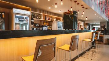 Zona de bar con barra, taburetes y estanterías llenas de botellas.