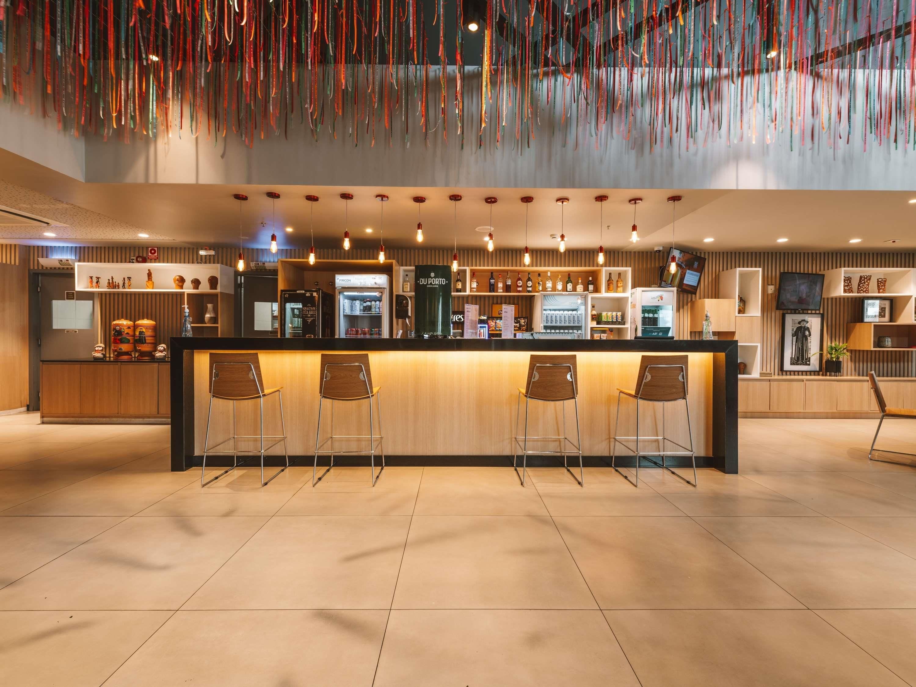 Un área de bar moderna con mostrador de madera, taburetes y una variedad de botellas de licor.