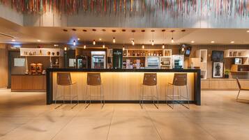 Un área de bar moderna con mostrador de madera, taburetes y una variedad de botellas de licor.