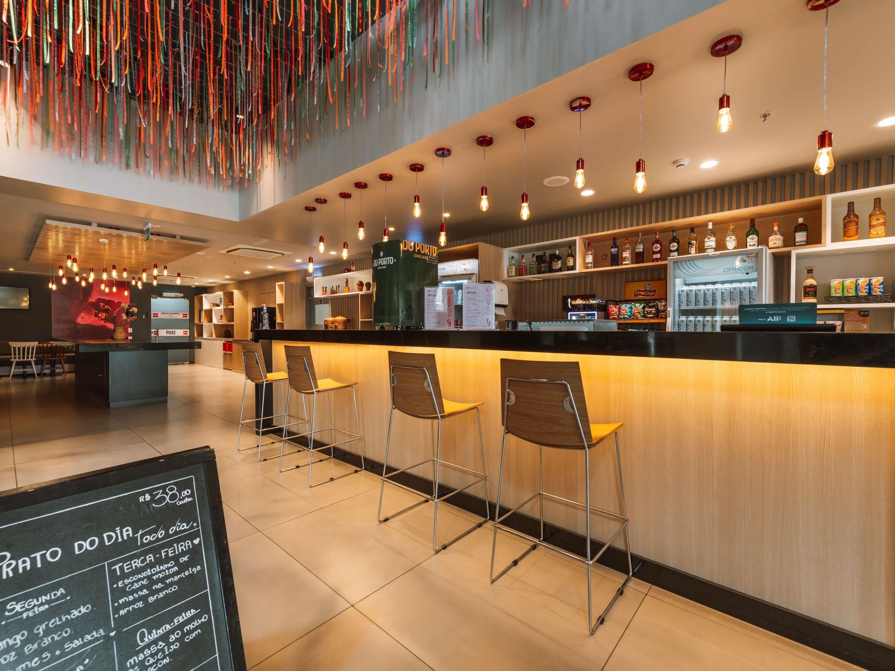 Un'area bar con un bancone, sgabelli e una lavagna per i menu.