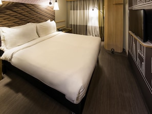 A hotel room with a large bed, a bedside table with a lamp, a TV, and curtains. - Ibis Juazeiro do Norte (Juazeiro do Norte)