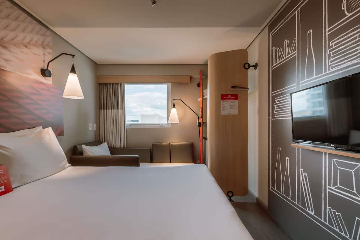 Ein Hotelzimmer mit Bett, Schreibtisch, Fernseher und Fenster mit Blick.
