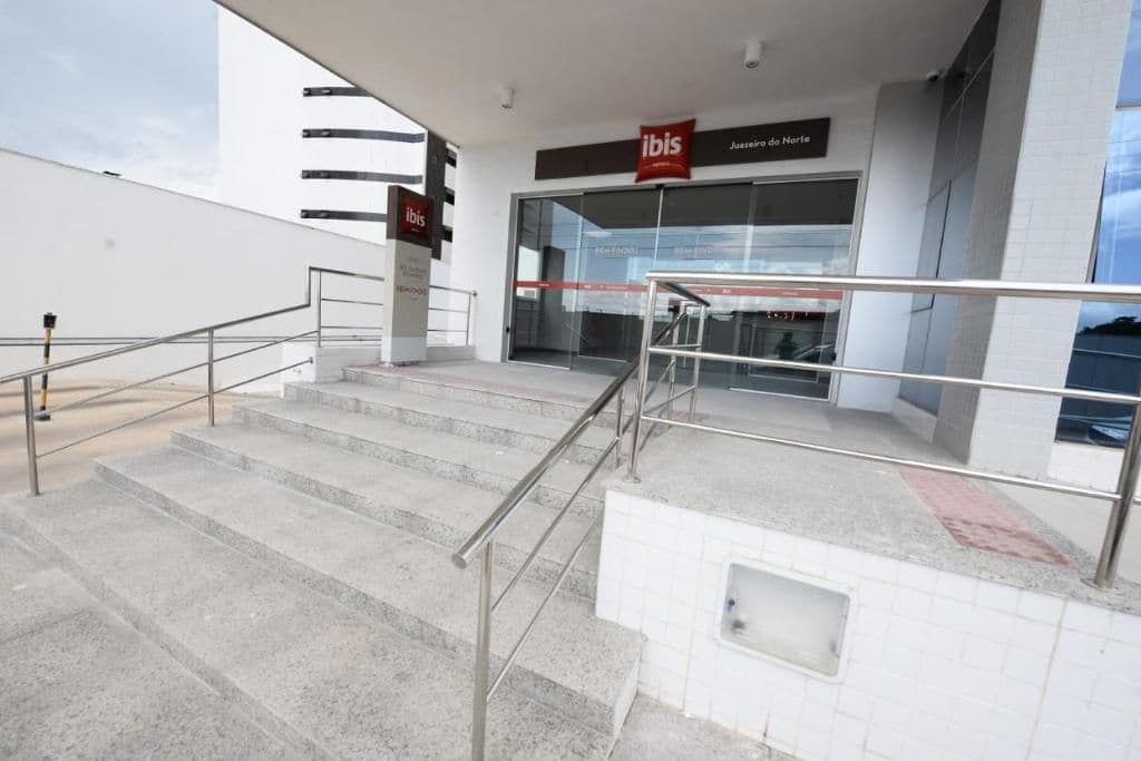A set of outdoor stairs leading to a building entrance with a glass facade and a sign reading 'ibis Juazeiro de Norte.'