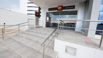 A set of outdoor stairs leading to a building entrance with a glass facade and a sign reading 'ibis Juazeiro de Norte.'