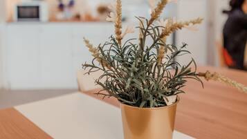 Una planta en maceta con hojas largas y delgadas y pequeñas flores sobre una mesa de madera.