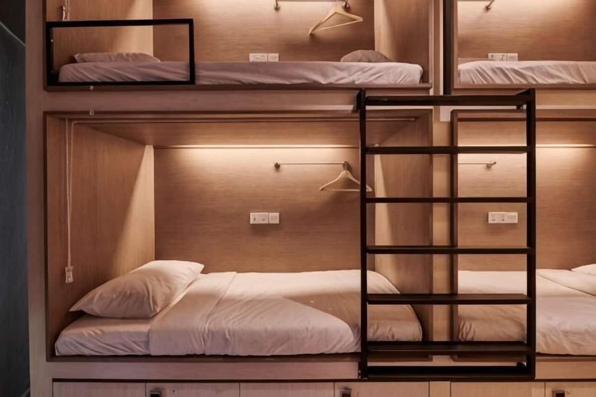 A bunk bed room with a ladder, wooden walls, and a hanging light fixture.