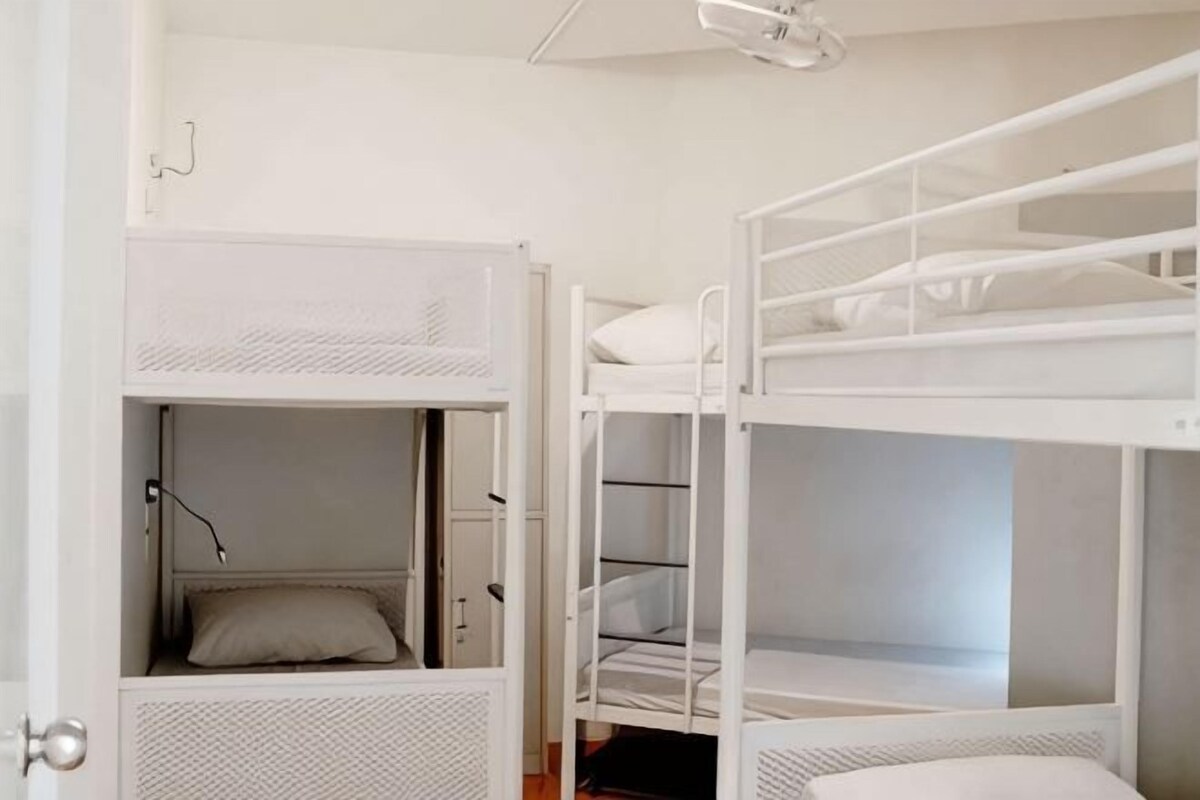 A room with bunk beds, a door, and a ceiling light fixture.