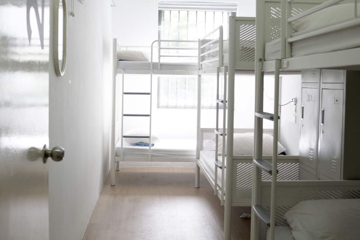 A bunk bed room with a window, a door, and a metal locker.