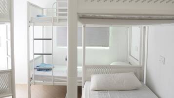 A bunk bed room with a window, white walls, and a wooden floor.
