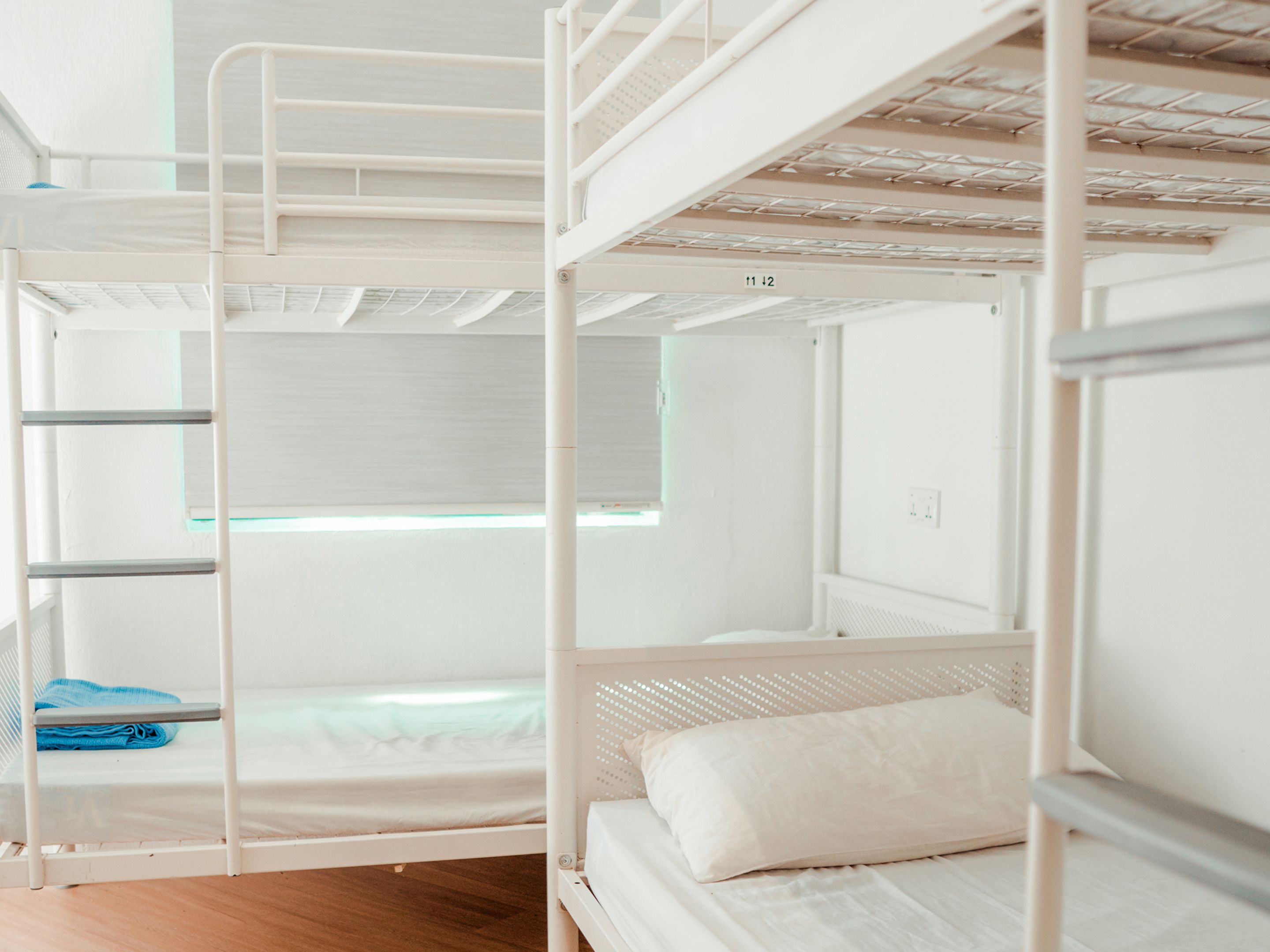 Une chambre avec un lit superposé, une fenêtre, une serviette bleue et un oreiller blanc.