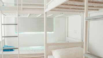 Une chambre avec un lit superposé, une fenêtre, une serviette bleue et un oreiller blanc.
