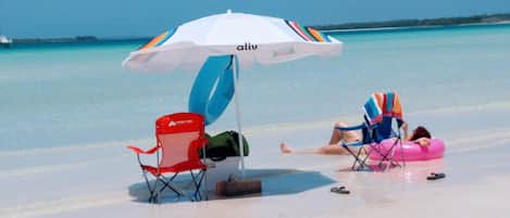 A beach scene with a white umbrella labeled "aliv", a red beach chair, and a pink inflatable float.