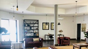 Ein geräumiges Wohnzimmer mit dunklem Holzboden, Ledersofas und einem großen Bücherregal.