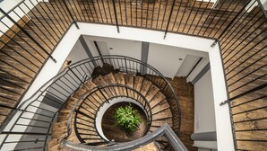 Eine Wendeltreppe mit Holzboden und Metallgeländern, die zu einer oberen Etage führt.