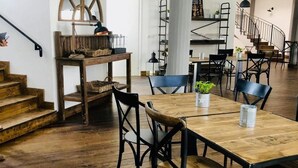 Ein geräumiger Essbereich mit Holztisch und Stühlen, eine Treppe im Hintergrund und eine moderne Küche, die durch eine offene Tür sichtbar ist.