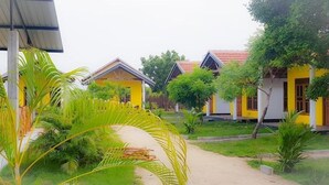 A row of yellow buildings with a pathway leading through a garden area. - Exotic Beach Hotel (Pottuvil)