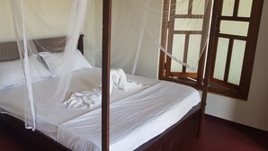 A bed with a canopy, a window with wooden frames, and a red floor. - Exotic Beach Hotel (Pottuvil)