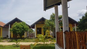 A row of yellow buildings with red-tiled roofs, surrounded by greenery and a wooden fence. - Exotic Beach Hotel (Pottuvil)