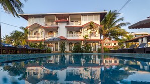 A hotel with a large pool, multiple balconies, and palm trees. - La Vaiencia Beach Resort (Morjim)