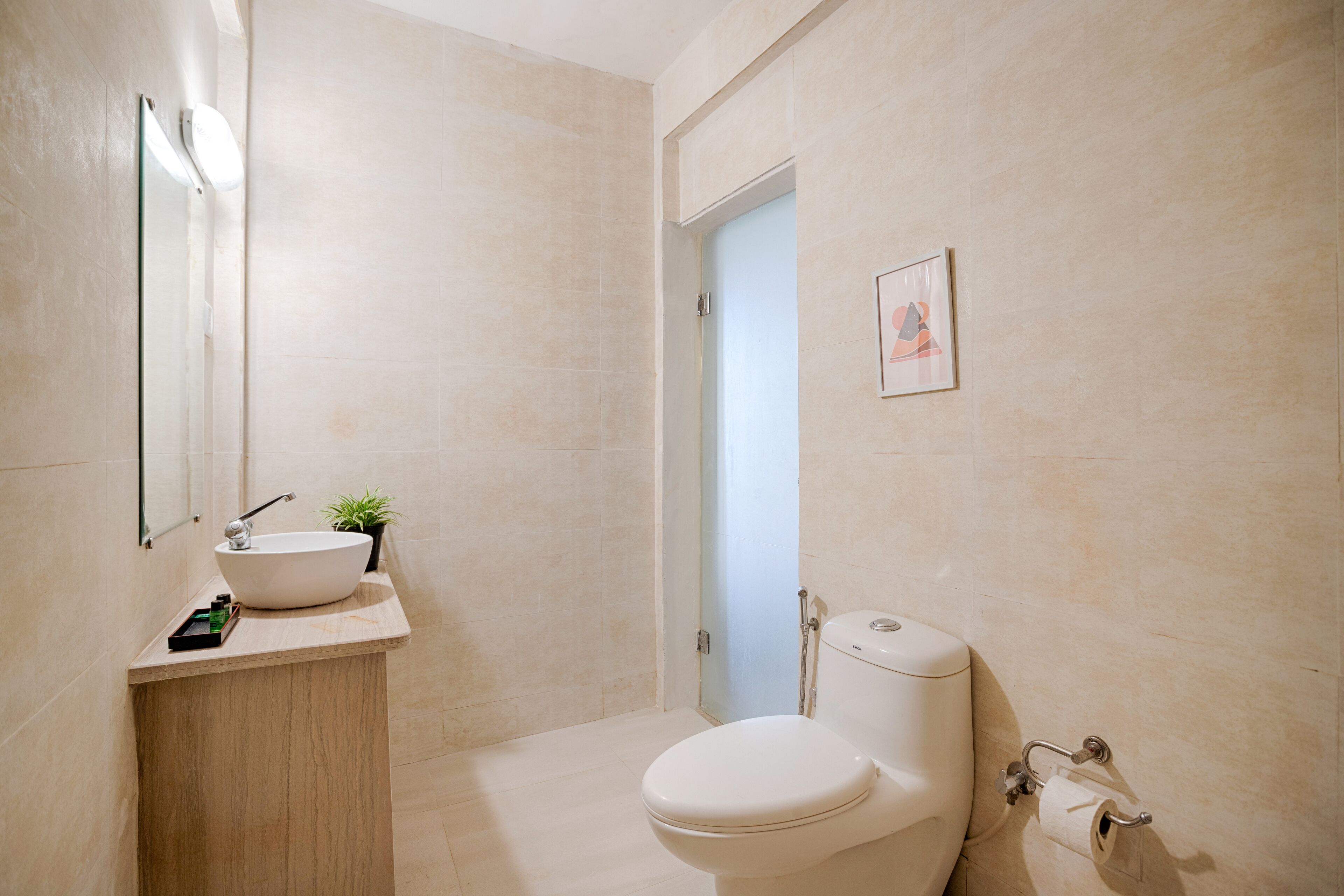 Een moderne badkamer met een groot wastafel, toilet en een kleine plant in pot.