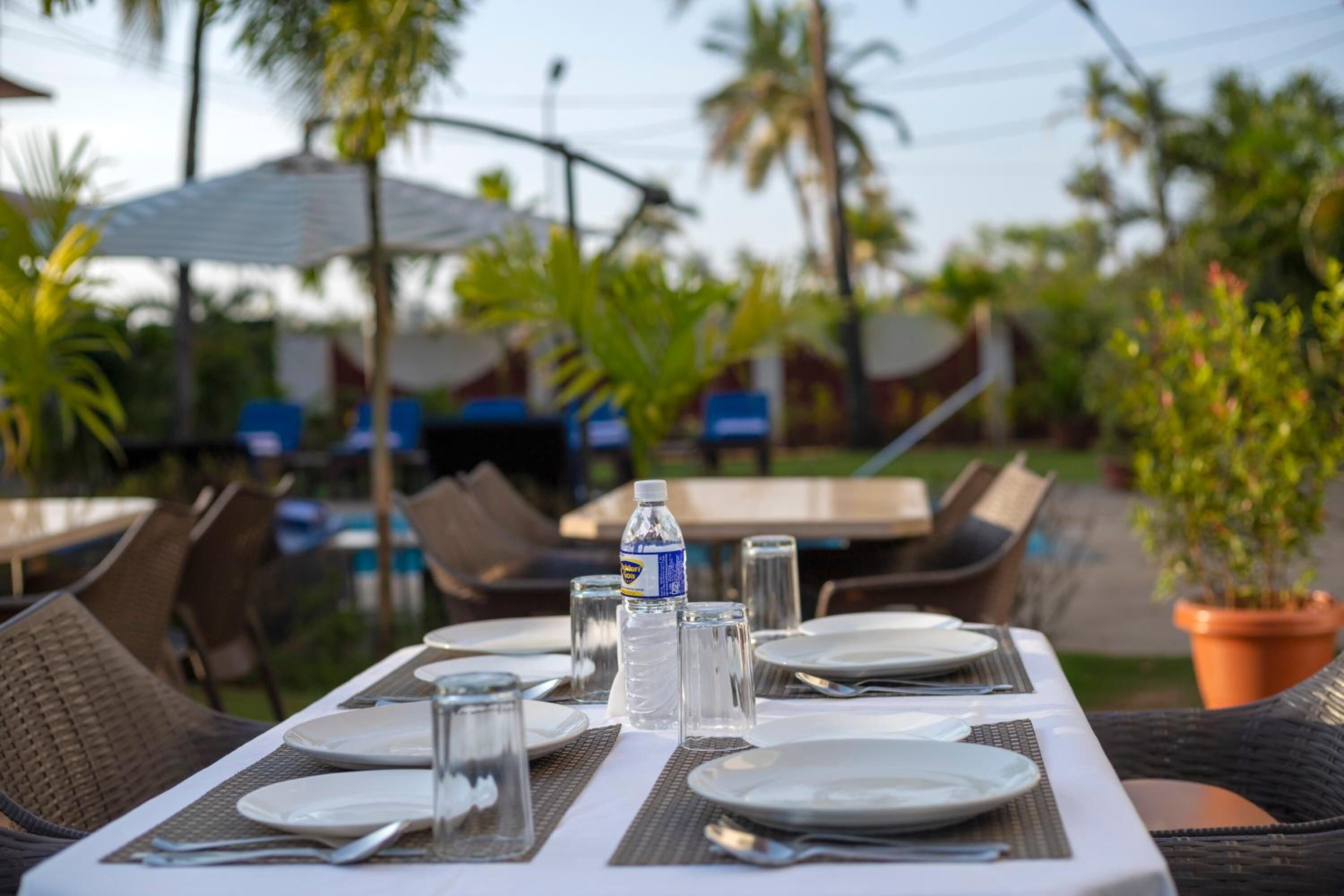An outdoor dining area with tables set for two, equipped with plates, cutlery, and glasses.