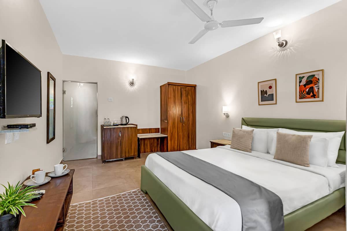 Un dormitorio con cama, escritorio, televisor, armario y ventilador de techo.