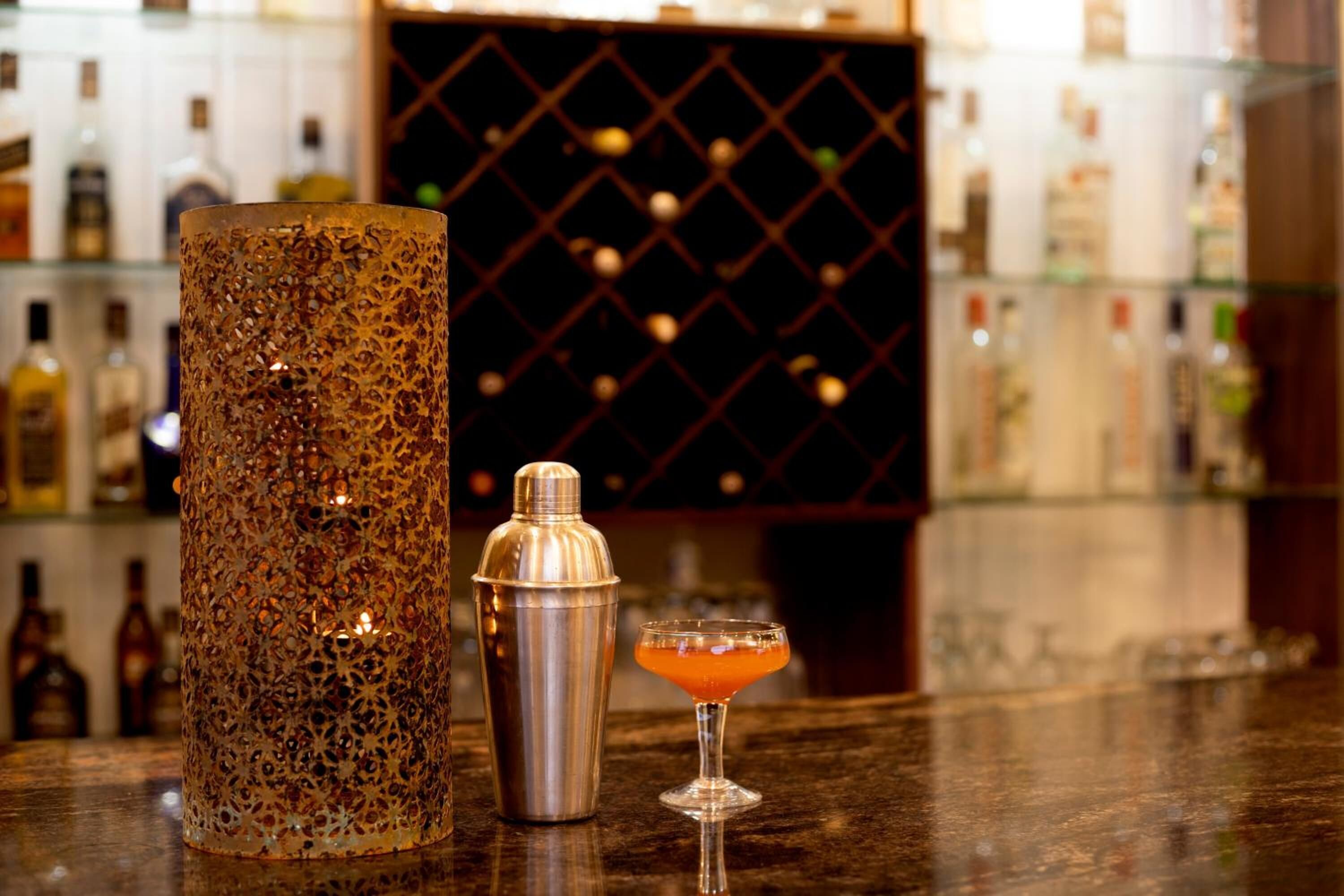 A bar area with a decorative metal container, a cocktail shaker, and a martini glass on a counter.