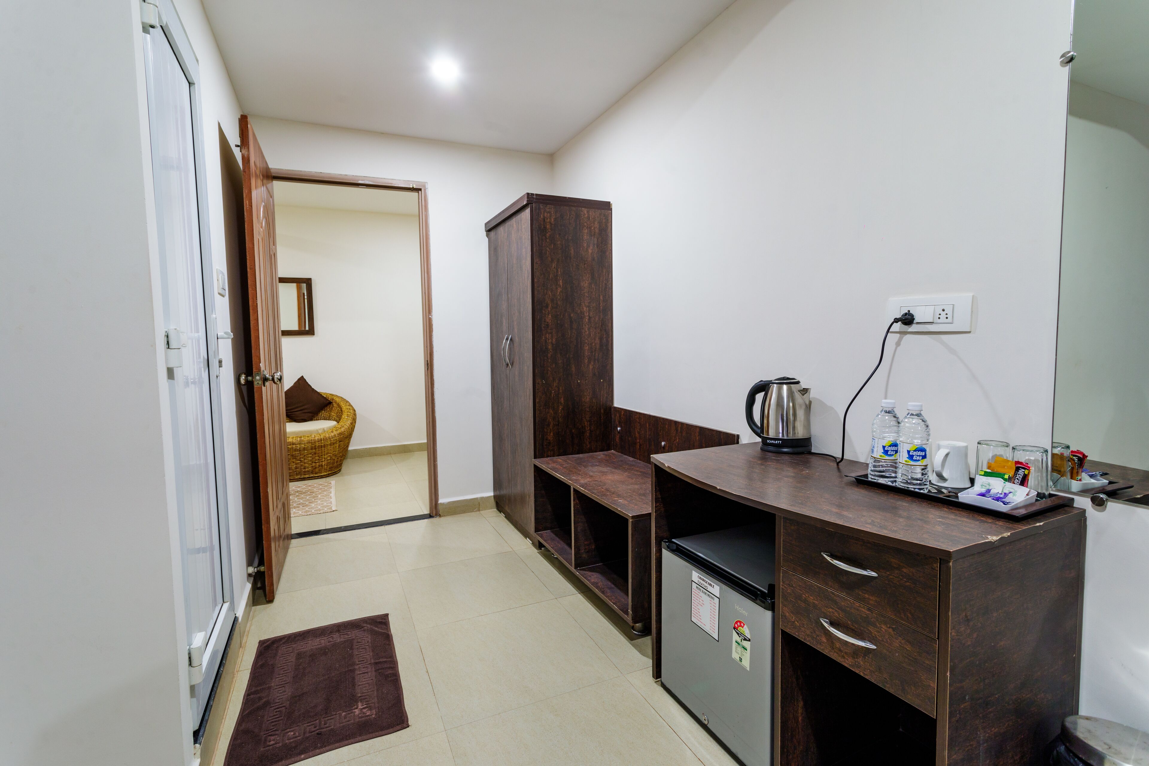 A compact kitchenette with a refrigerator, a coffee maker, and a small cabinet.
