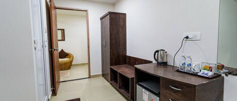 Una kitchenette compacta con refrigerador, cafetera y un mueble pequeño.