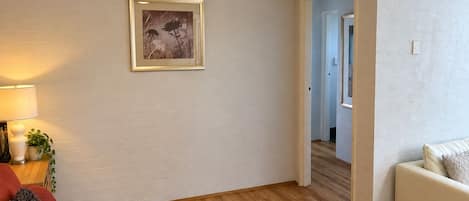 A living room with a sofa, a lamp, a framed picture, and an air conditioning unit.