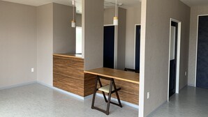 Une pièce moderne et minimaliste, dotée d’un bureau en bois, d’une chaise et d’un luminaire suspendu.