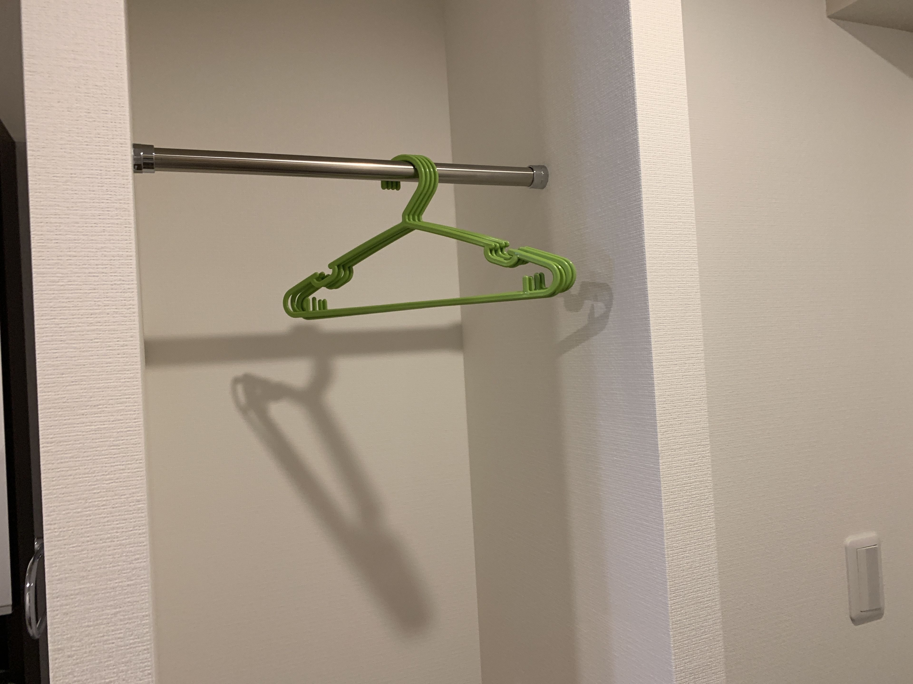 A bathroom with a towel rack and a green hanger.