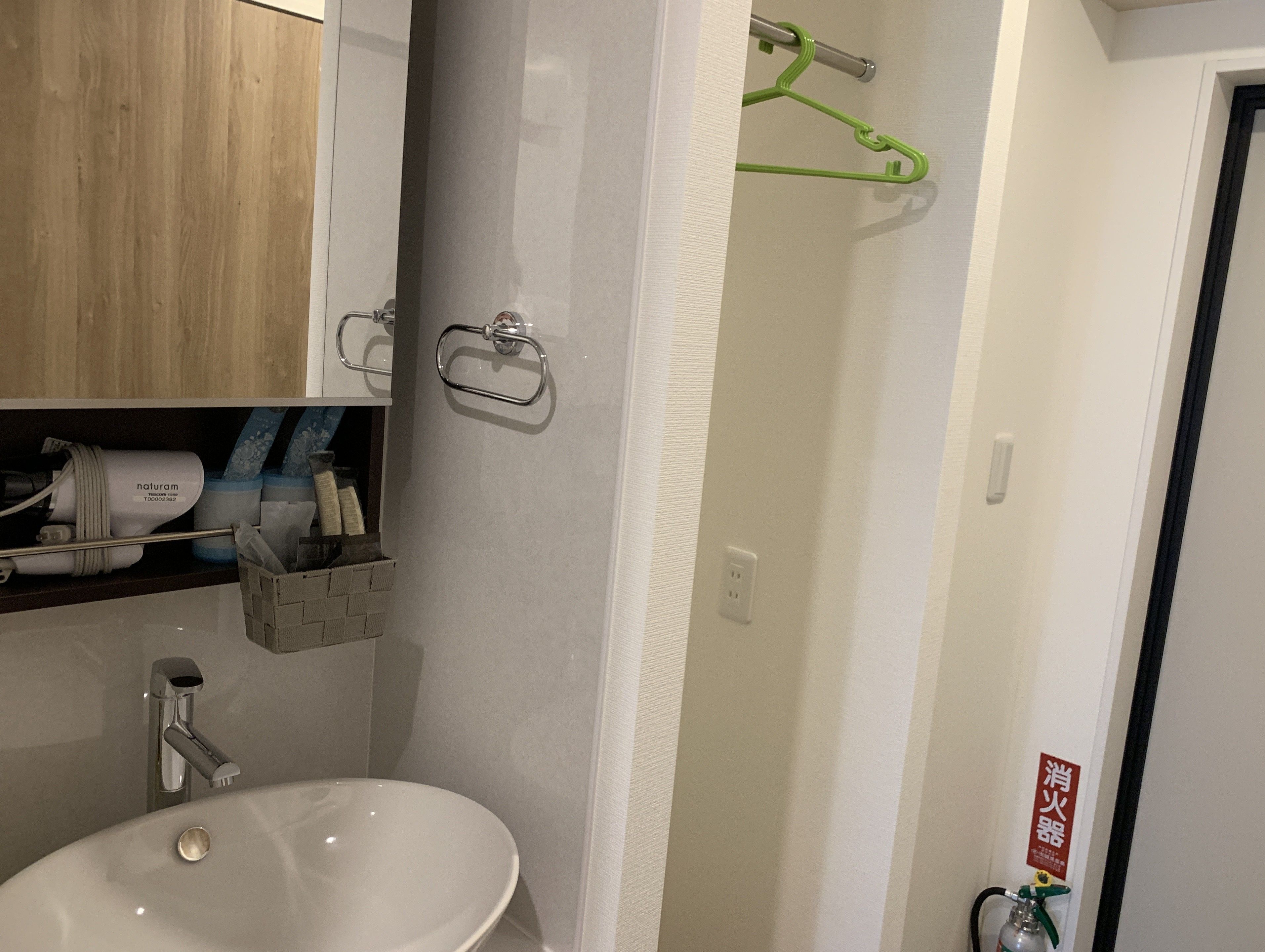 A bathroom with a white sink, a mirror, a wooden cabinet, and a shower area.