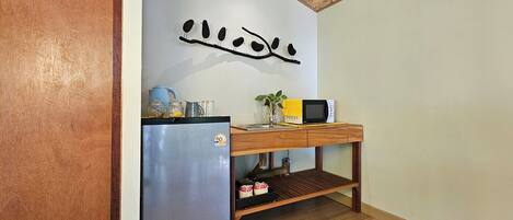 A compact kitchen with a refrigerator, microwave, and wooden countertop.