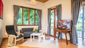 A living room with a sofa, a chair, a coffee table, a TV, and large windows with curtains. - Luxury Farm House (Pai)