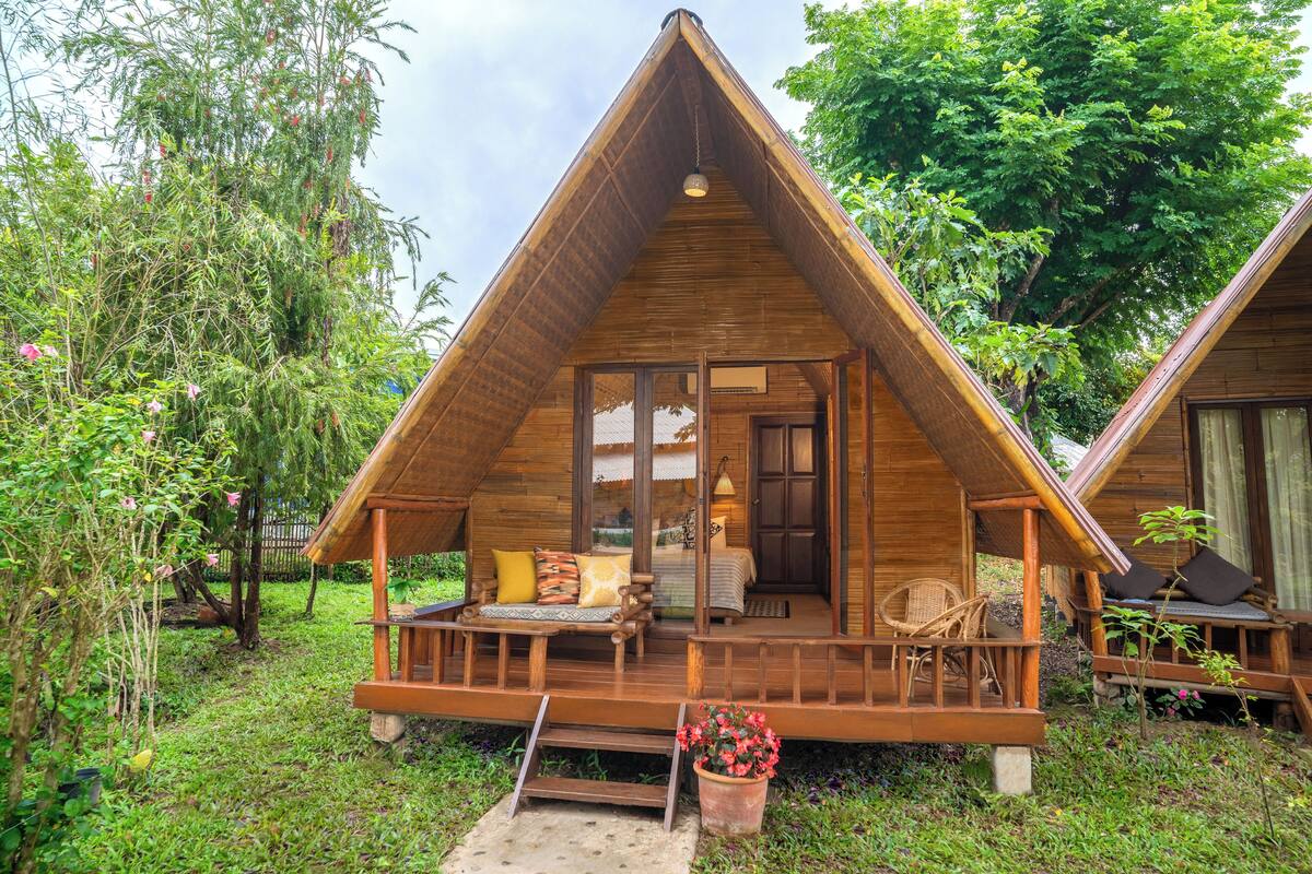 A wooden cabin with a porch, a bed, and a seating area.