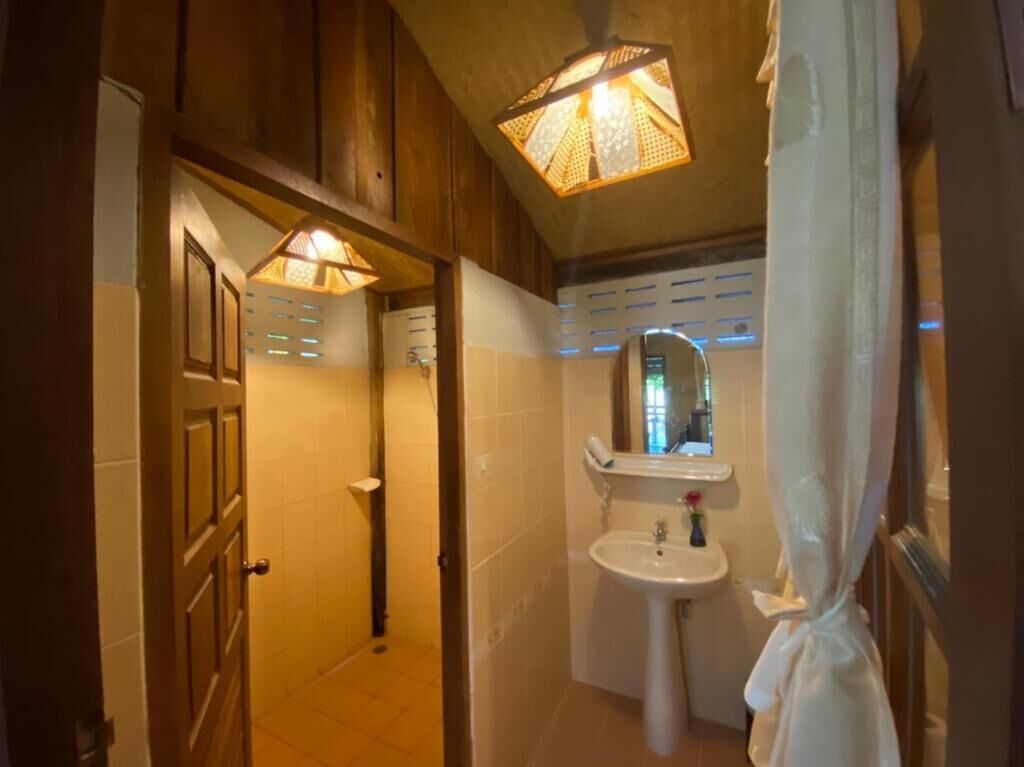 A bathroom with a wooden door, a sink with a mirror, and a shower area.